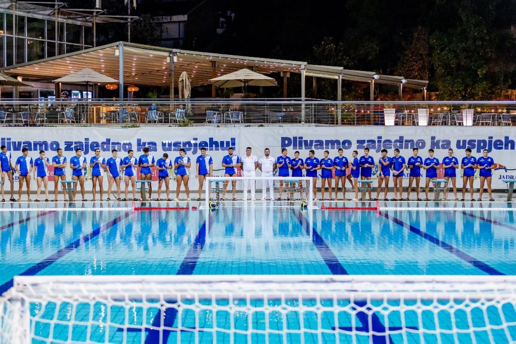 Vaterpolisti i sudije poređani uz bazen prije utakmice